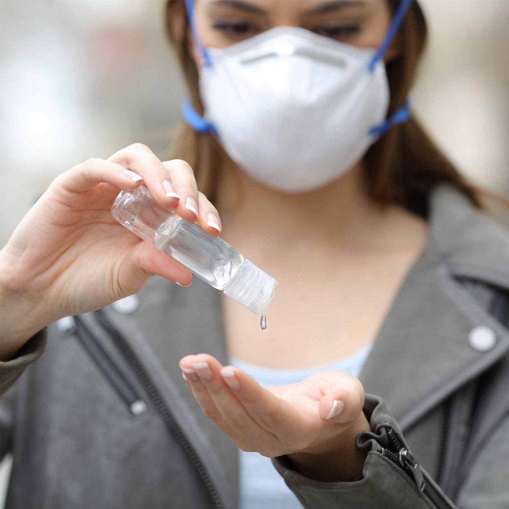 Woman with mask using hand sanitizer preventing contagion